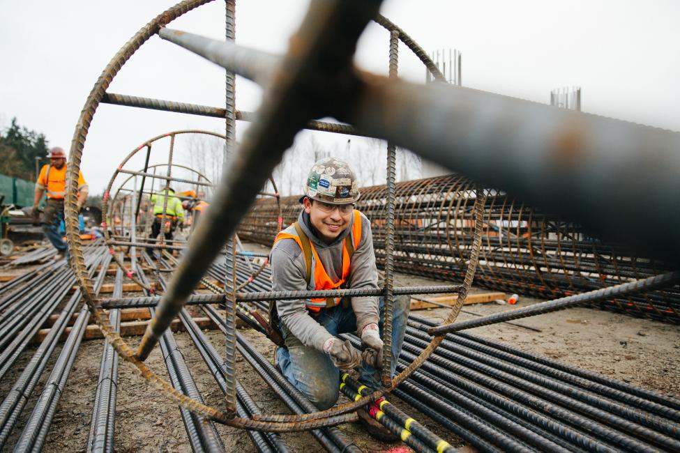 2018 in review: an ironworker smiles for the camera while wiring rebar together
