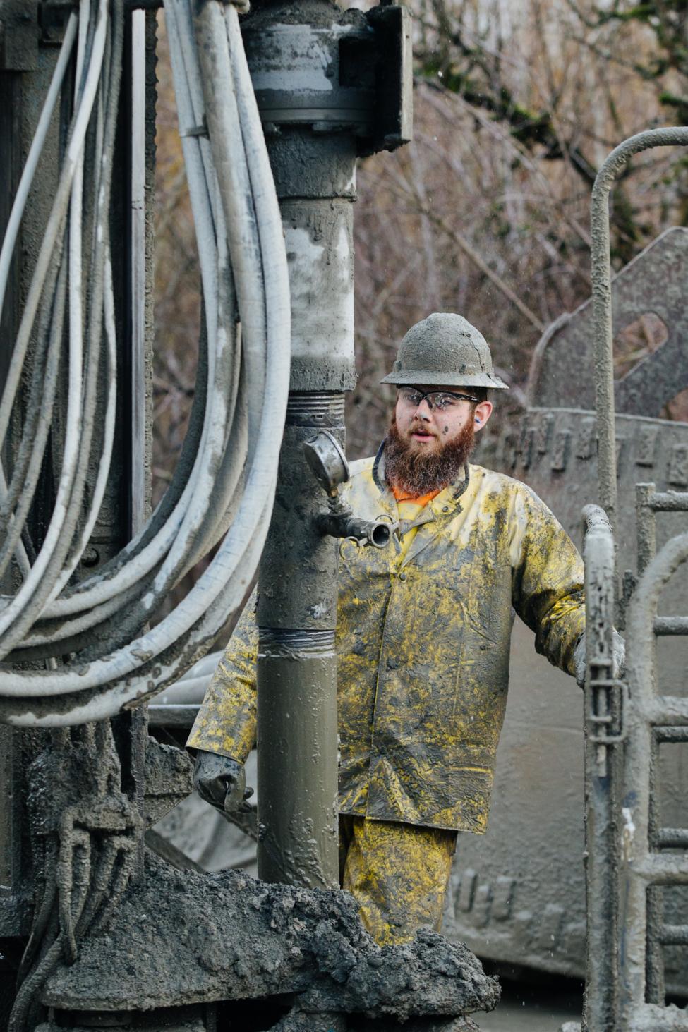 2018 in review: a worker covered in mud next to a drilling rig