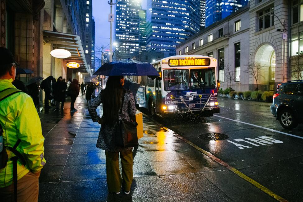 2018 in review: commuters with umbrellas prepare to board a Sound Transit Express bus in downtown Seattle