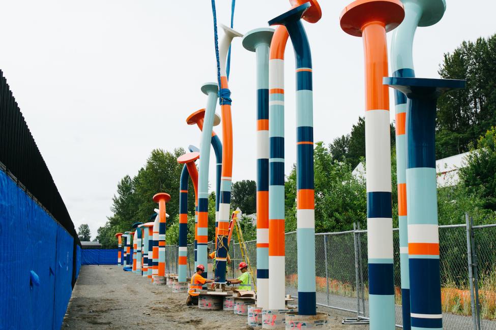 Workers install a colorful 20-foot tall "nail" sculpture along the Eastrail Trail.