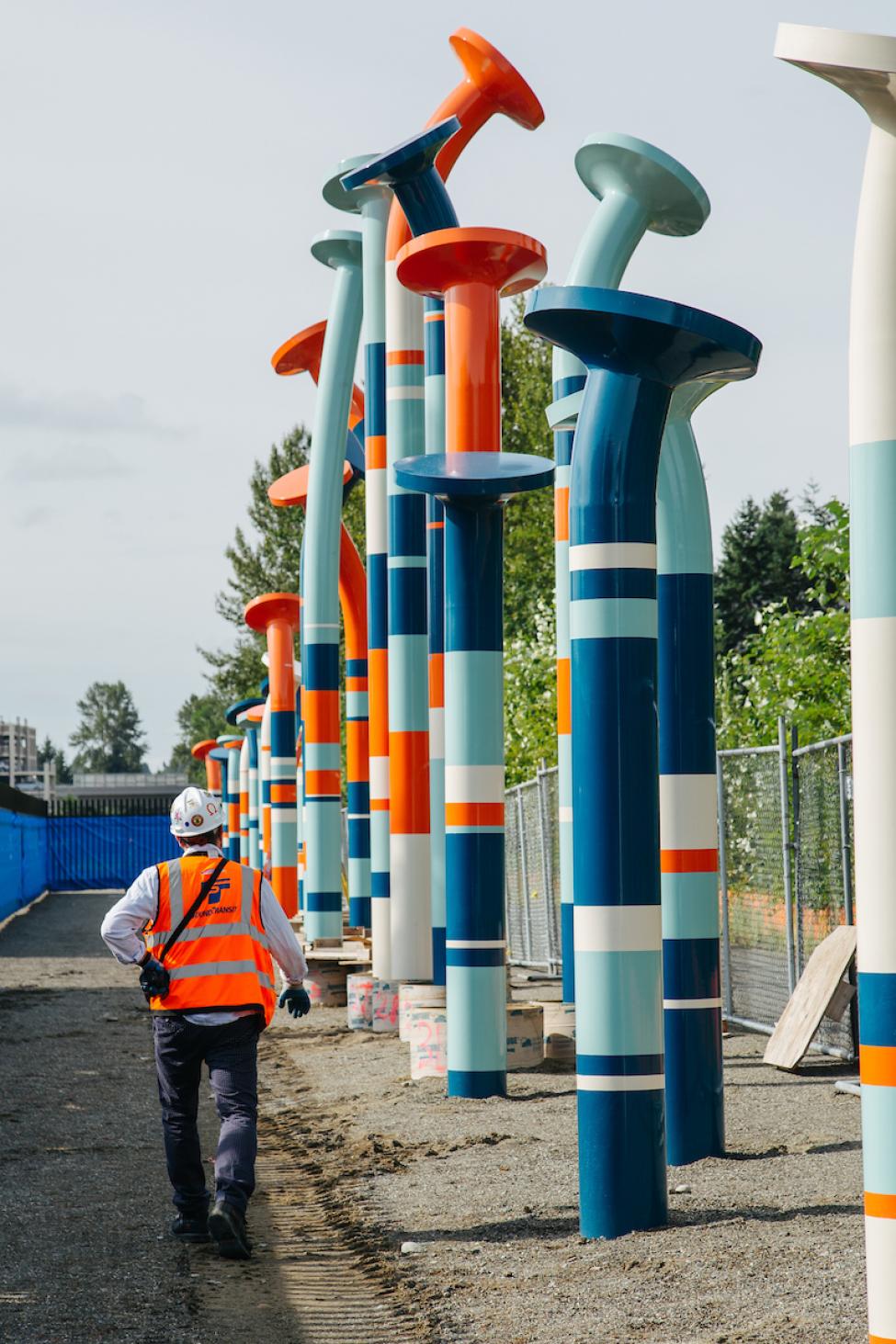 A man walking next to the 20-foot tall "nails" sculpture along the Eastrail Trail in Bellevue.