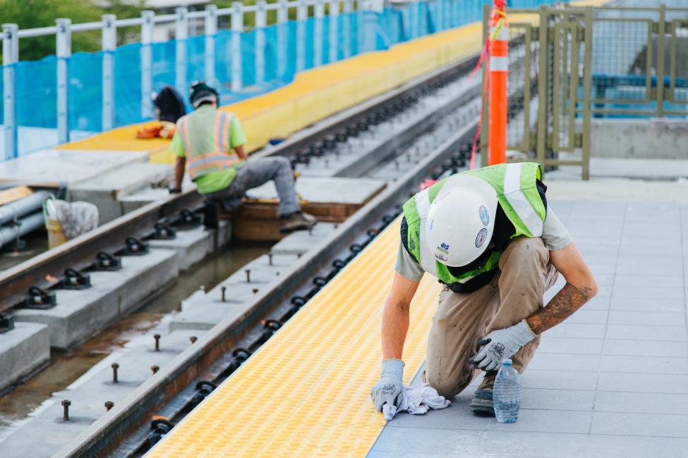 Construction workers focus on tile and track work at the Northgate Station platform.