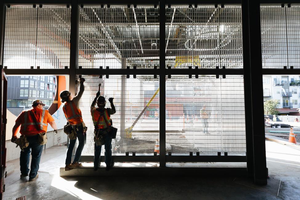 Three construction workers work on the north headhouse of Roosevelt Station.