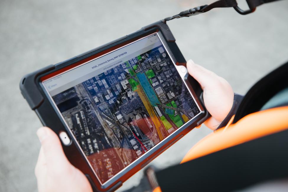 A woman uses a tablet and detailed mapping software to take note of potential significant historic resources in Seattle.