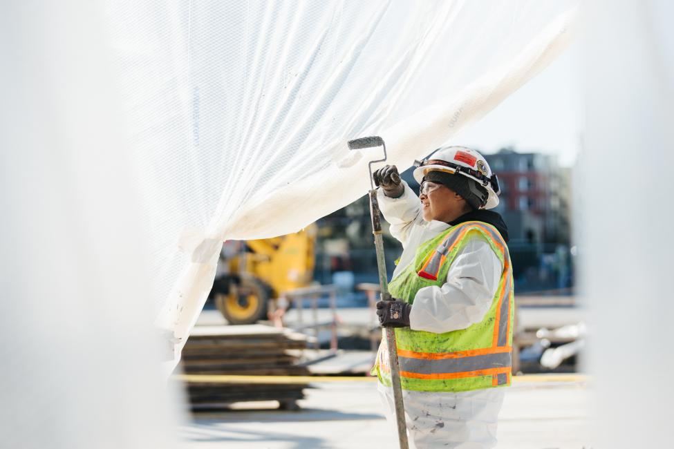 A construction worker paints portions of the station under white plastic sheets.