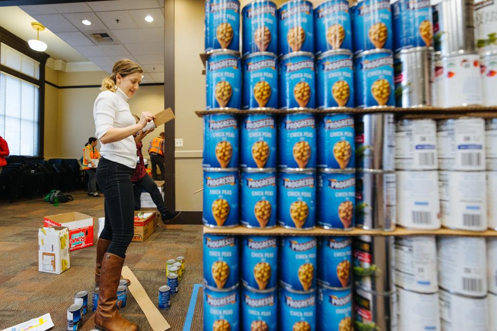 A woman, Ariel Taylor, helps build a structure out of canned food.