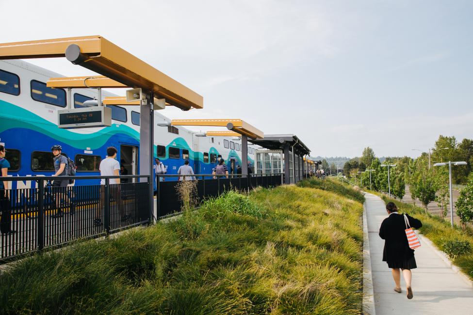 A woman walks on a sidewalk by the Tukwila Sounder Station.