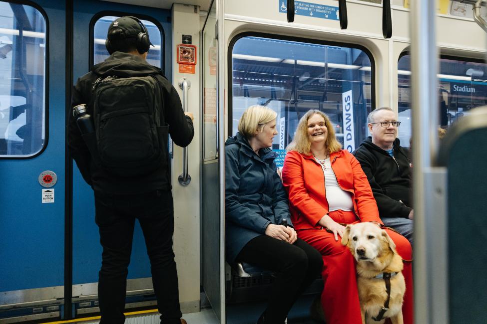 A woman with a seeing eye dog sits in the priority seating section of a Sound Transit light rail vehicle.