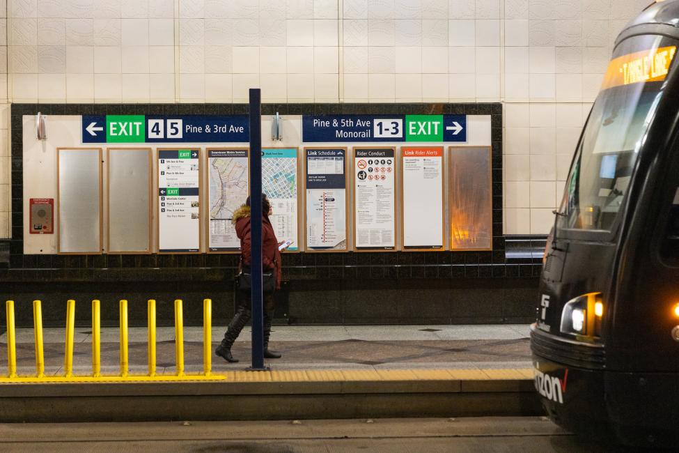 A rider walks past new directories and maps in Westlake Station that display information about the new numbered exits.