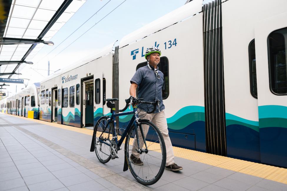 A rider approaching Link train at Angle Lake Station with his bike.