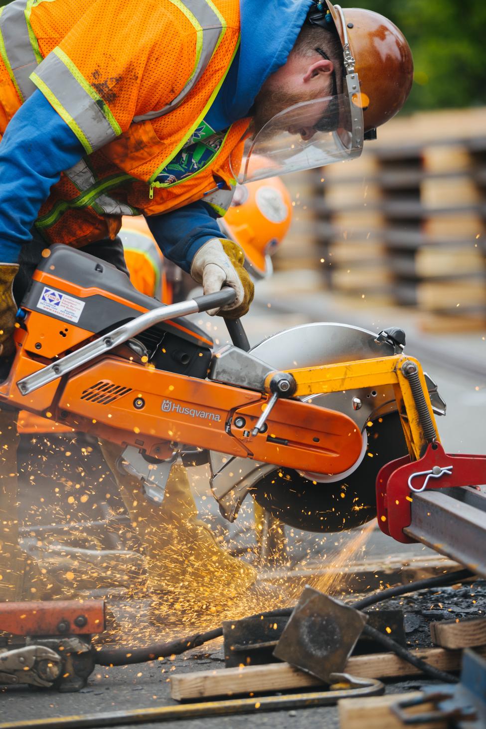 A worker in a hard hat and mask welds together pieces of rail for the Hilltop project in Tacoma.