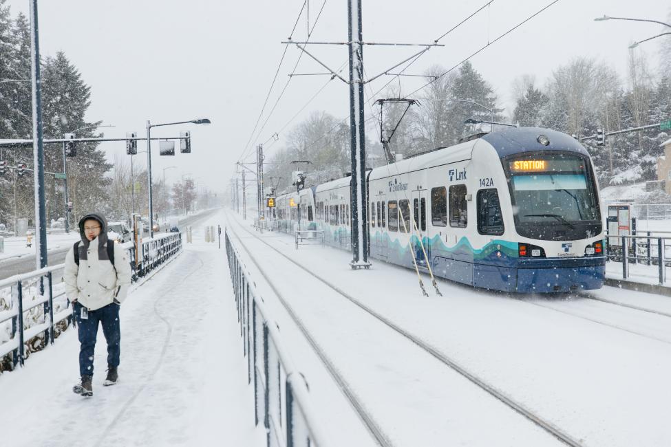 Link light rail runs along snow-covered tracks.