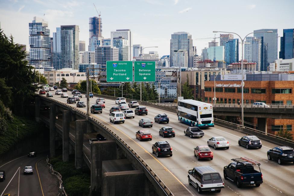 Cars and an ST Express Bus drive on I-5 South, with part of the Seattle skyline in the background.