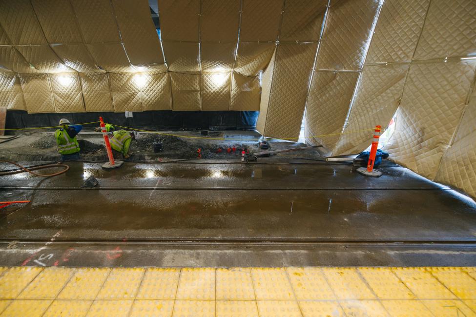 Two workers dig a trench to install new rail at International District/Chinatown Station.