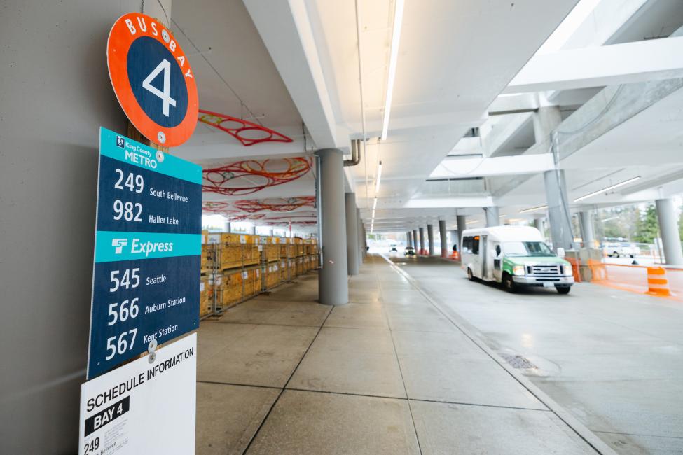 A sign reading "bus bay" in the foreground, with a shuttle in the background.