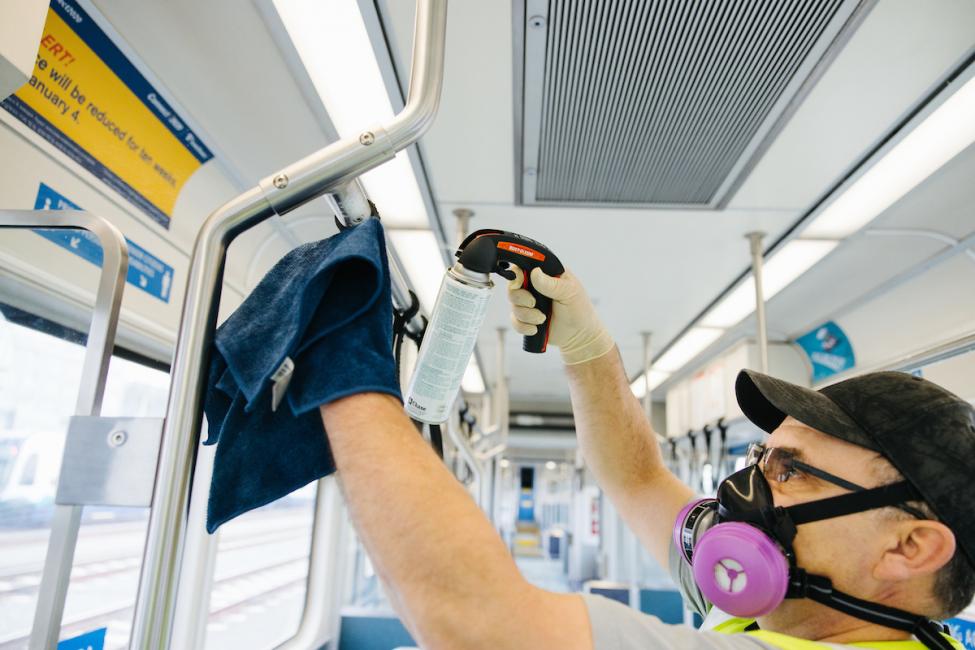 A worker cleans a Link light rail train with disinfectant. 