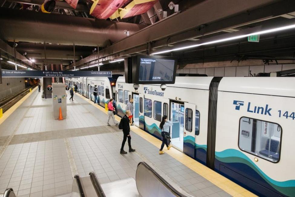 Passengers on a nearly empty platform board Link light rail.