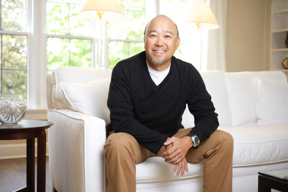 Sound Transit employee Alan Yamamoto smiles while sitting on a couch.