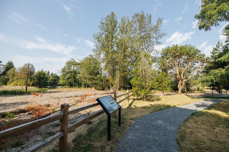 A fence and trail are pictured, with trees in the background. 