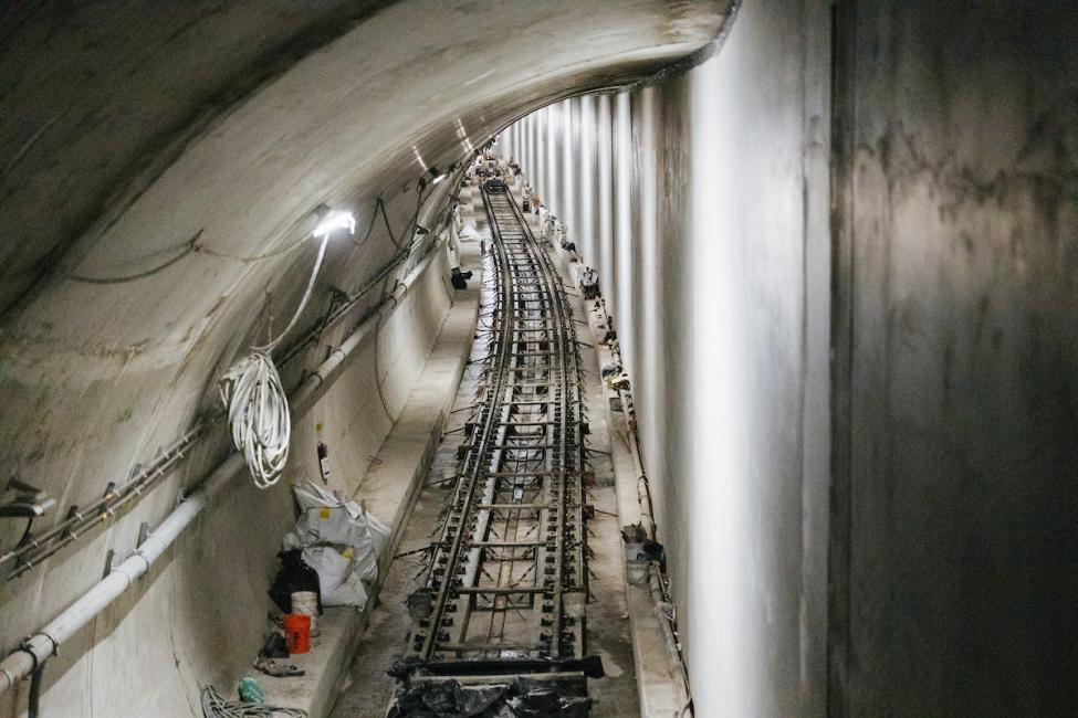 A view of the tracks in the downtown Bellevue light rail tunnel. Trains run on either side of a dividing wall that runs the length of the tunnel. 