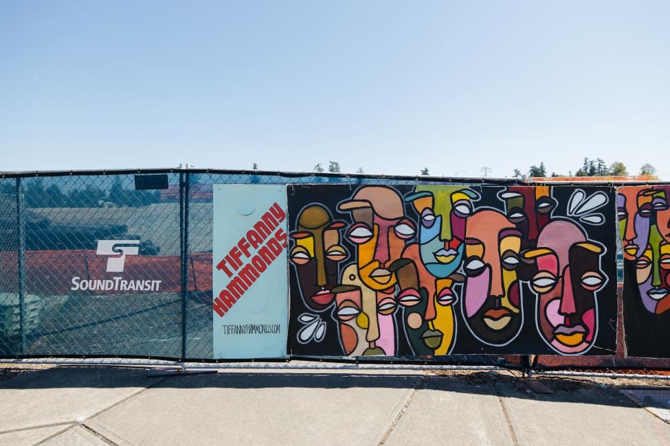 A mural by Tiffany Hammonds is displayed on a construction fence.