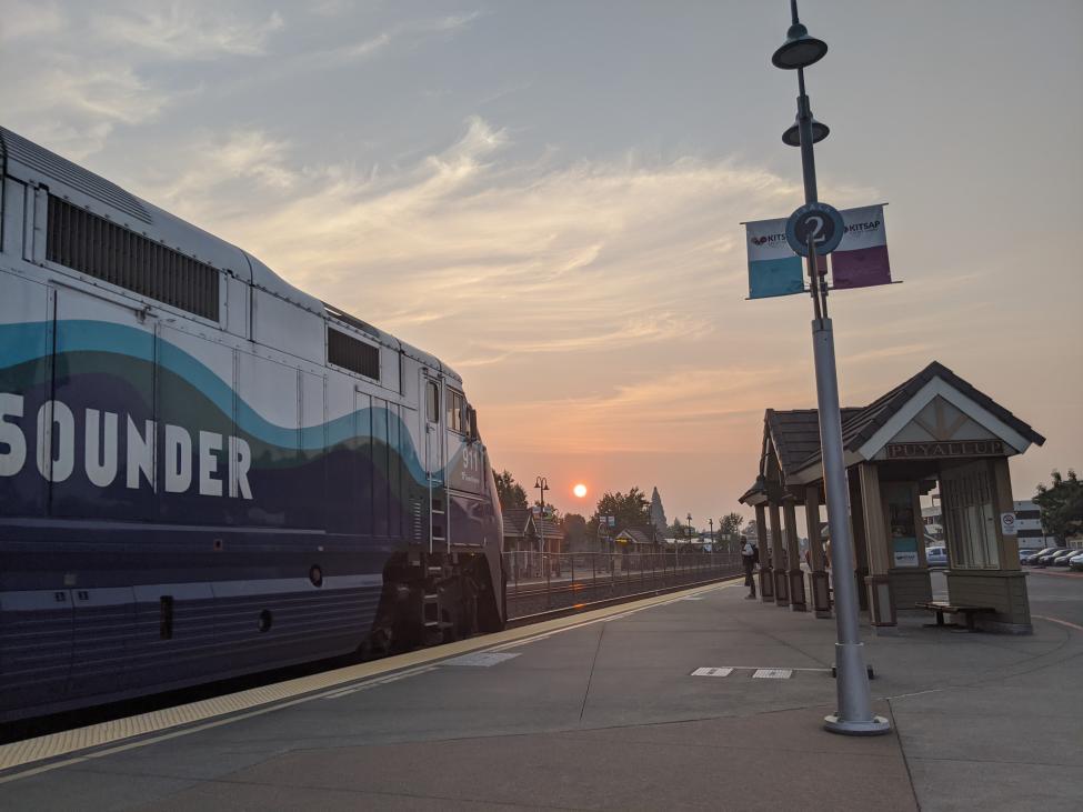 A Sounder train is pictured on the left of the photo, taken from a station platform at sunset.