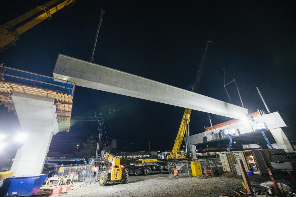 A large girder spans the space between two columns. This photo was taken at night. Big spotlights shine on the structure.