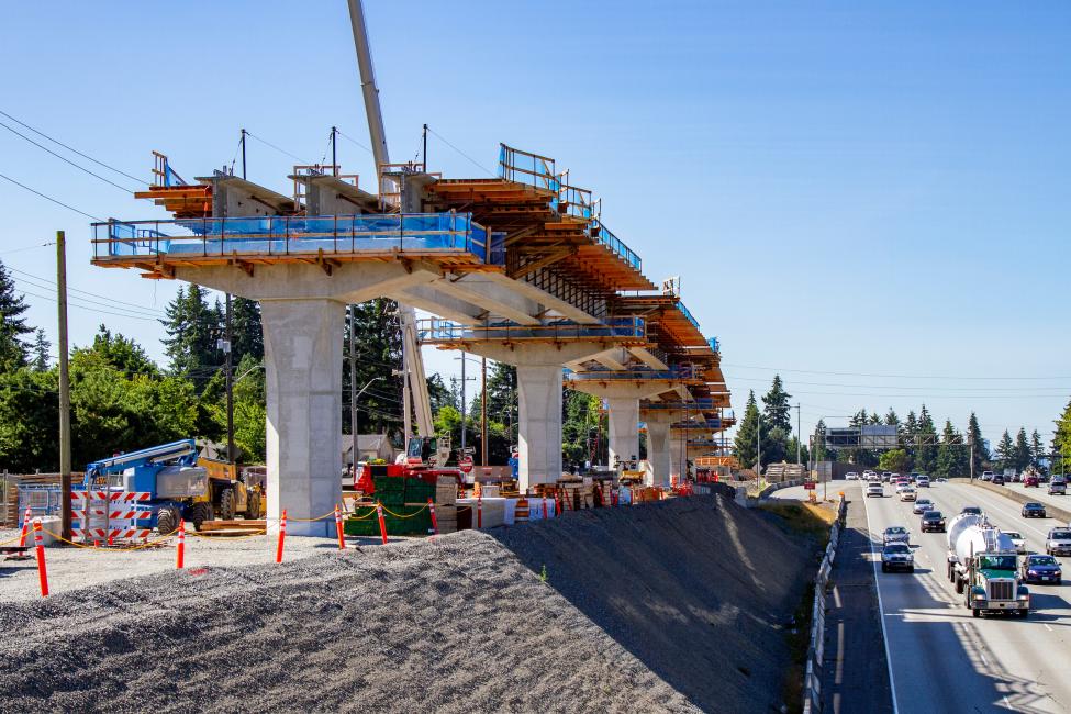 A light rail guideway is under construction next to I-5.