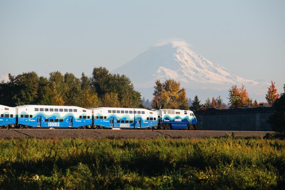 A Sounder train is pictured, with Mount Rainier in the background.