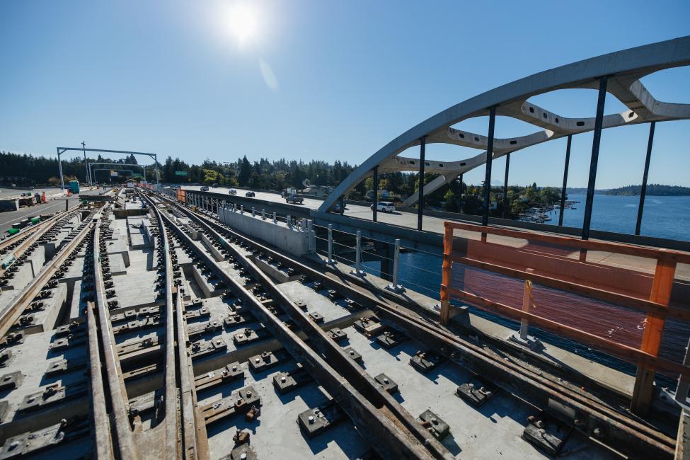 Lake Washington can be seen in the background as train tracks are being built on the I-90 floating bridge.