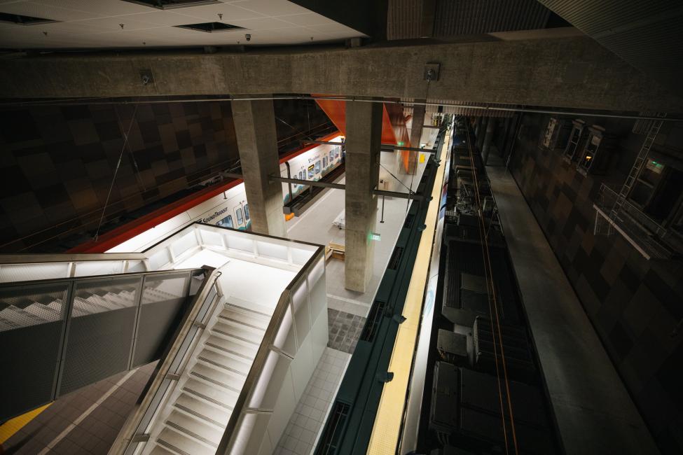 Looking down the stairs to the U District Station platform as trains roll through.