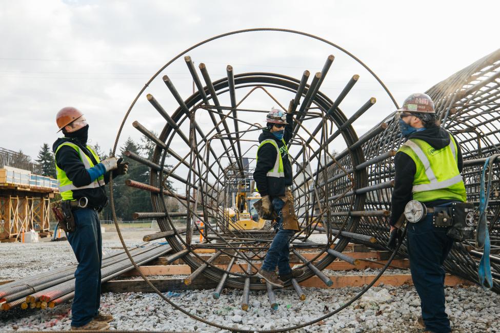 Ironworkers maneuver steel cages that will support columns at the future Kent/Des Moines light rail station. 