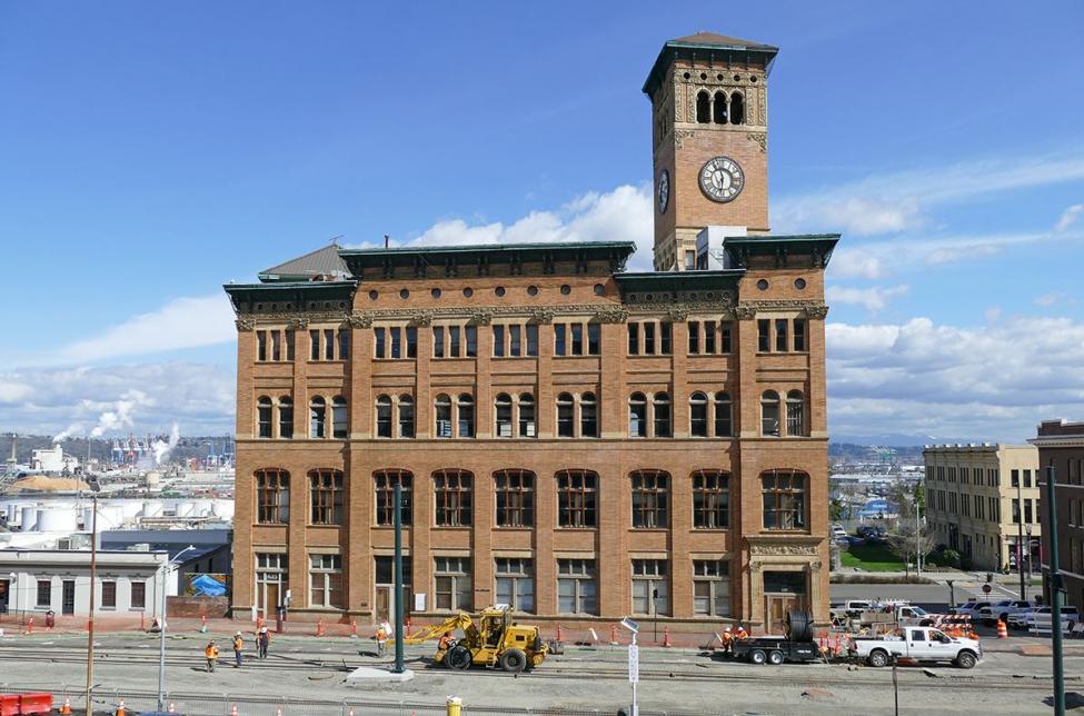Light rail track is installed in front of the old City Hall, a large brick building, in Tacoma.