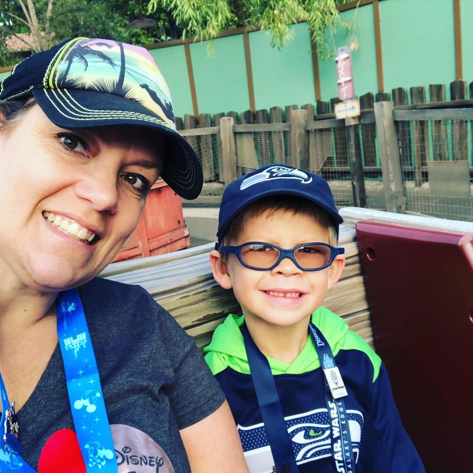 Kerry Pihlstrom and her son smile for a selfie while sitting on a ride at an amusement park.