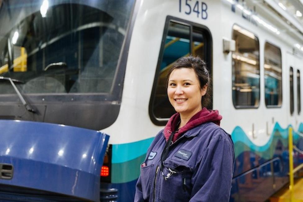Sound Transit employee stands in front of Link light rail train at an operations and maintenance facility