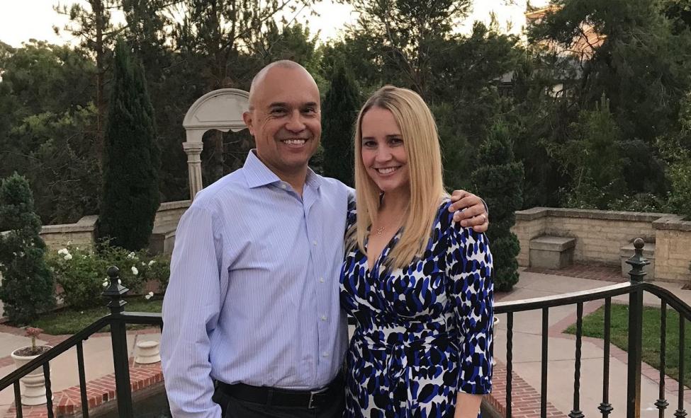 Jennifer Lemus and her husband Rudy smile for a photo, with green trees in the background.