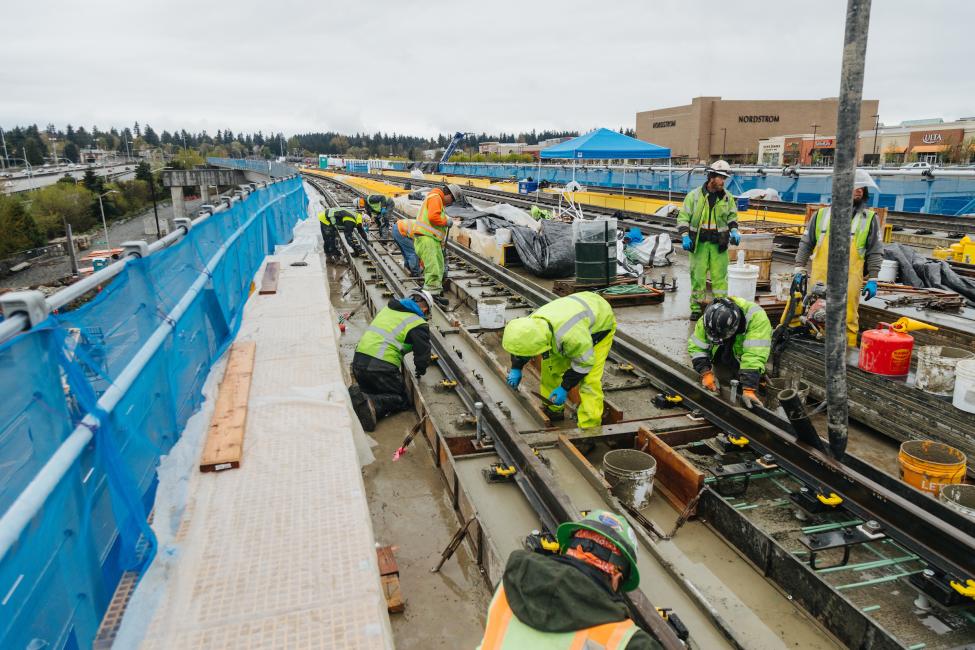 A half a dozen workers install rail on the elevated guideway near Northgate Station.