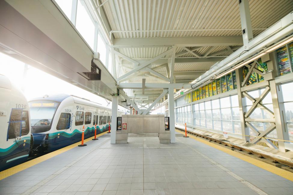 A Link train can be seen on the left side of the platform at Northgate Station, with stained glass art on the right.