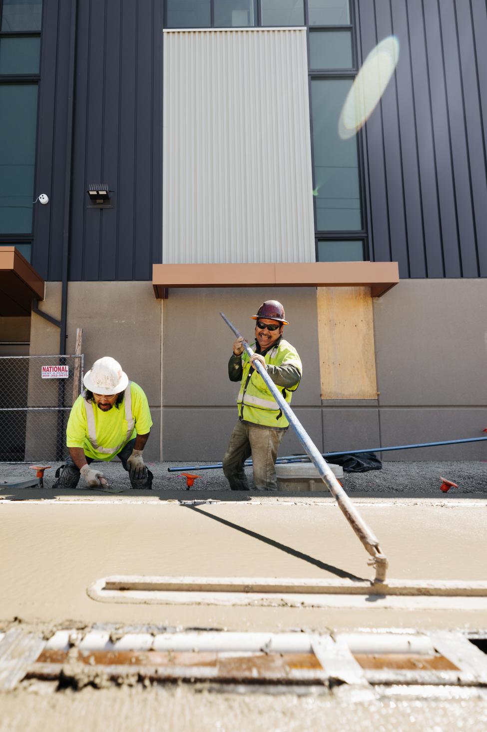 Two workers smooth concrete on the Tacoma construction site.