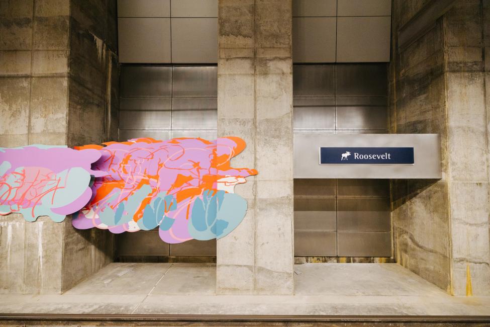 An art piece depicting cyclists is seen on the wall at the Roosevelt Station platform.