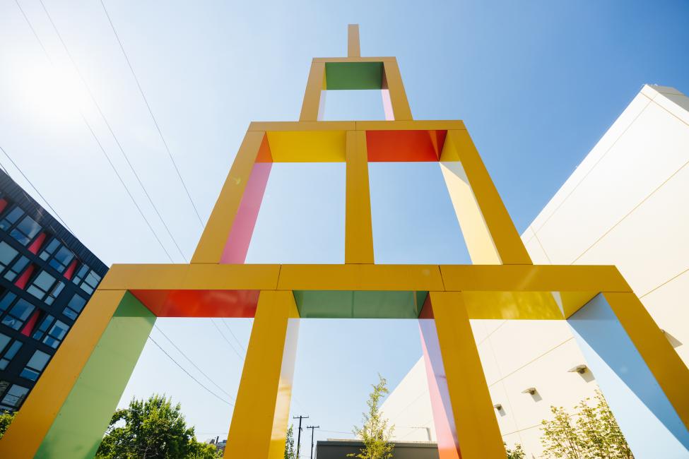 Looking up at a yellow sculpture that resembles the building block toys for kids. 
