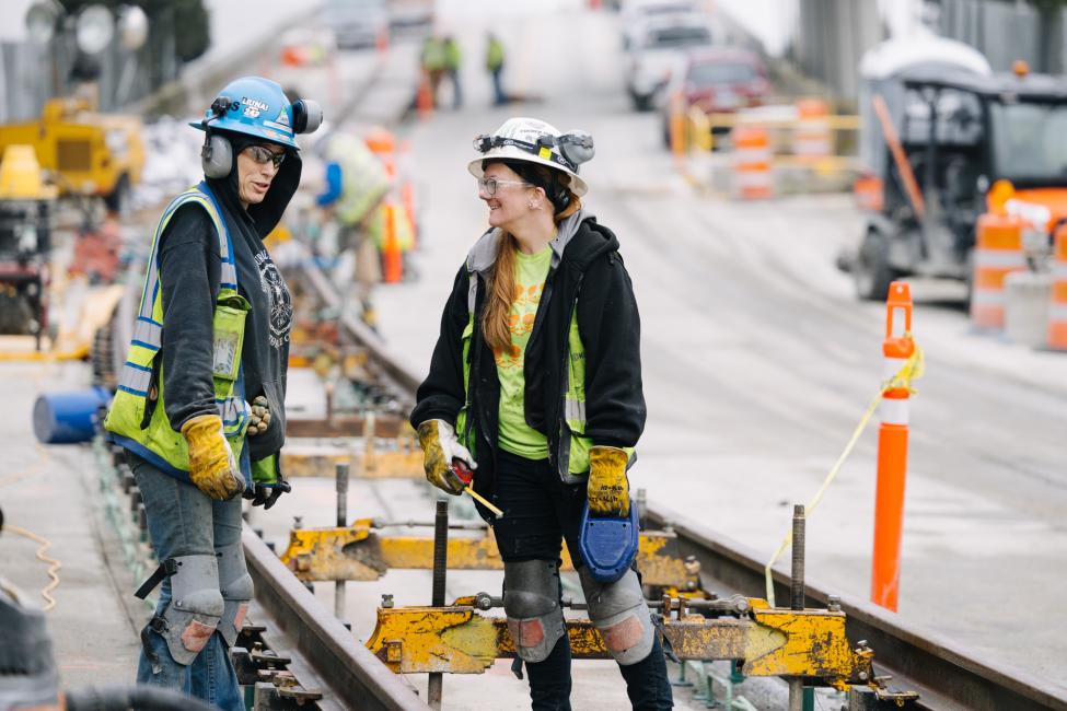 Two women work on a light rail construction site.