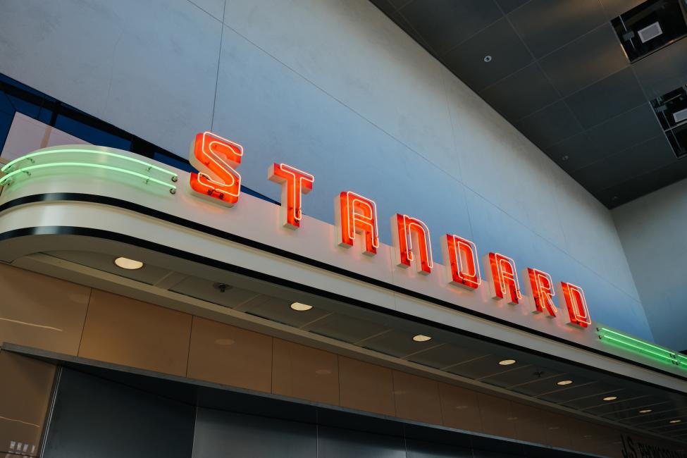 A neon sign lights up with letters that spell 'Standard.'