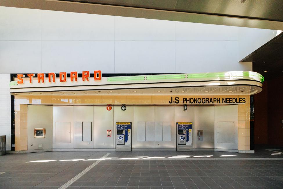 A neon sign that says 'Standard Radio' is above ticket vending machines at Roosevelt Station.