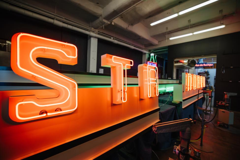 A neon sign lights up with letters that spell 'Standard.'