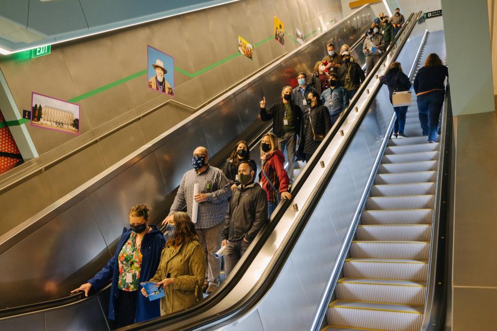 People wearing masks ride an escalator at Roosevelt Station.