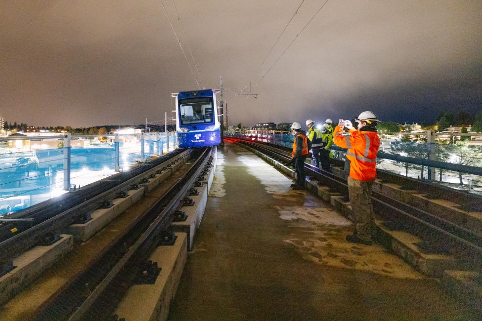 Crews watch as a test train is slowly pushed across the new light rail bridge over I-405 coming into downtown Bellevue.