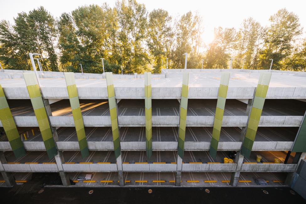 Sun shines on a parking garage with trees in the background.