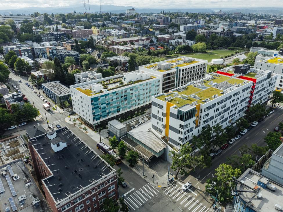 Looking down from an aerial drone photo of Capitol Hill Station where new apartment buildings surround the station with Cal Anderson Park in the background. 