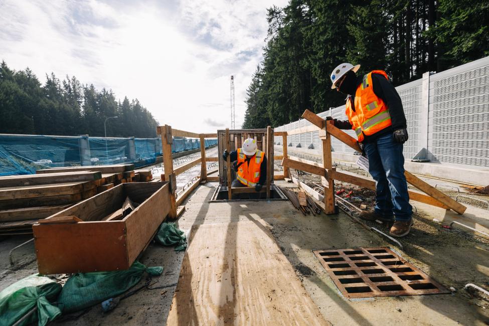 A construction worker climbs down a ladder into the bridge.